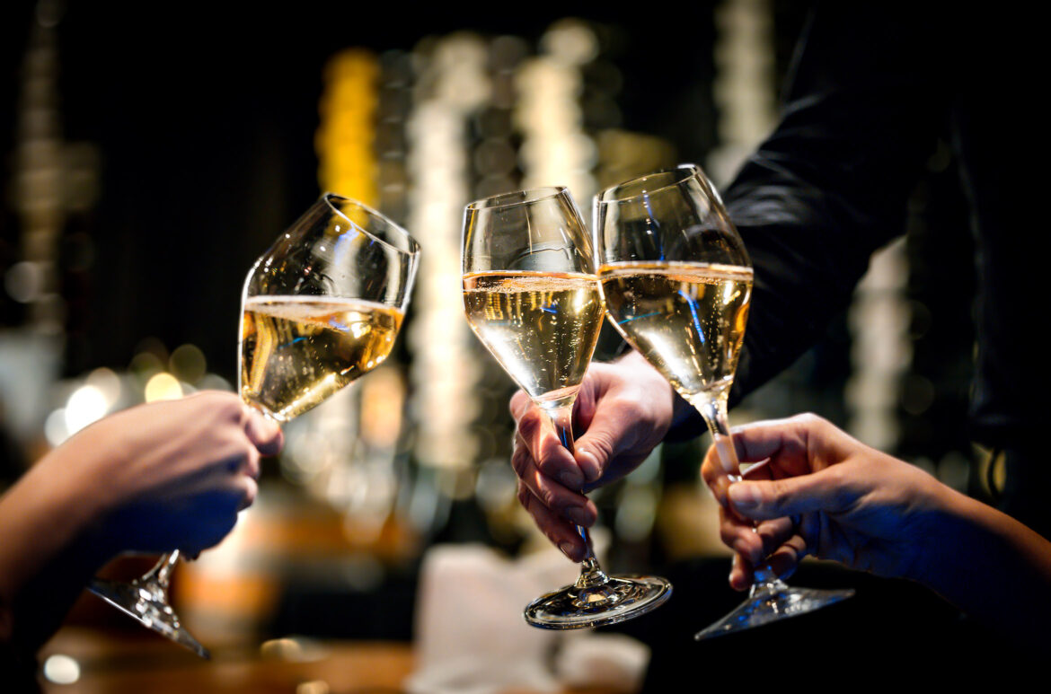 Three people cheers their full wine glasses at Cornucopia Whistler.